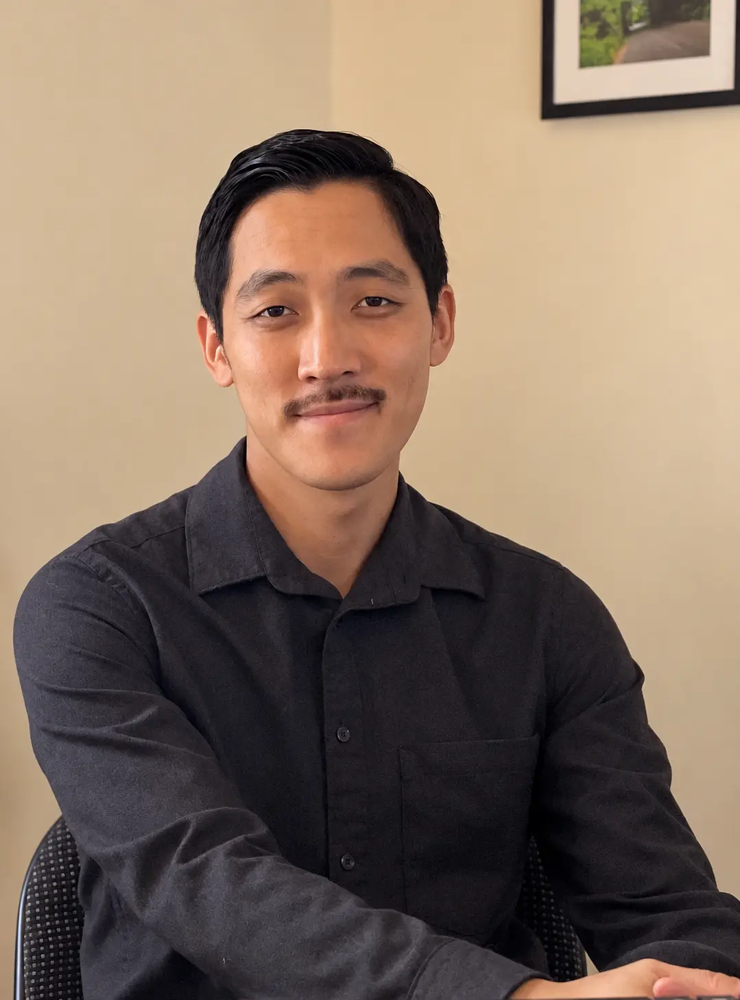 Chiwoo Choi smiling in a dark shirt against a warm wall